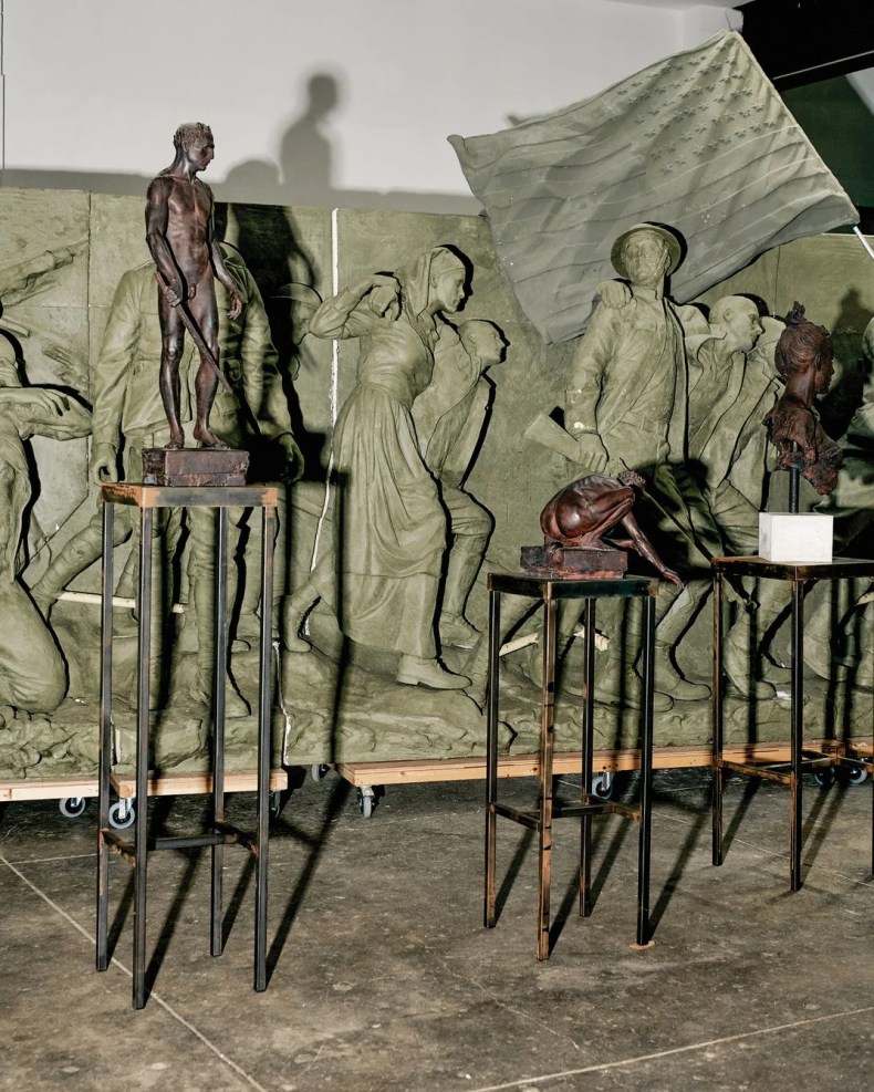 bronze and clay sculptures sit in a room