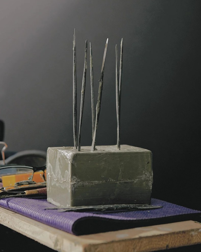 tools stuck into a block of clay